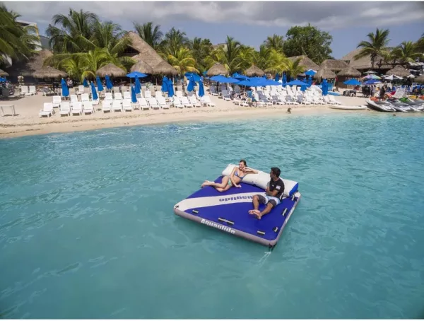Couple Floating on Giant Floating Mattress With Cooler on beach
