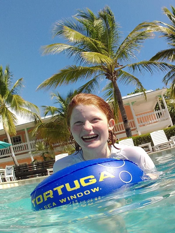 Girl Smiling And Swimming With Snorkling Floating Device With A Sea Window