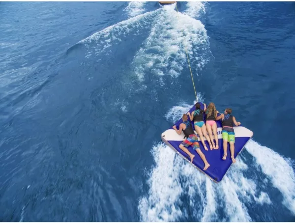Group Being Towed on Giant Floating Mattress With Cooler By Boat