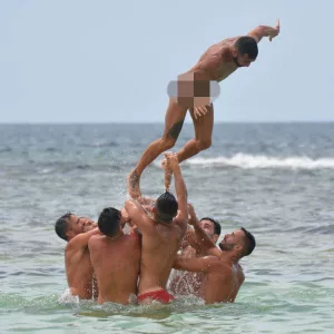 Group of Guys Throwing A Man In The Air In Prank Dissolving Swim Trunks