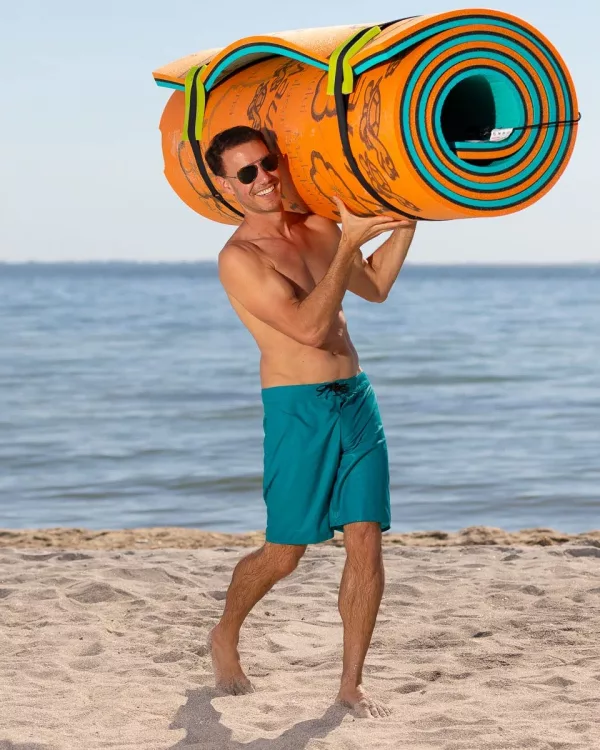 Man Carrying Giant Water Mat On Beach