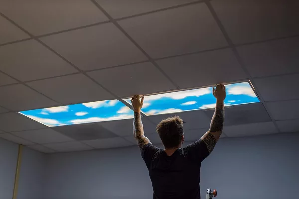 Man Installing Blue Sky Panel Light Fixture Cover In ceiling lighting