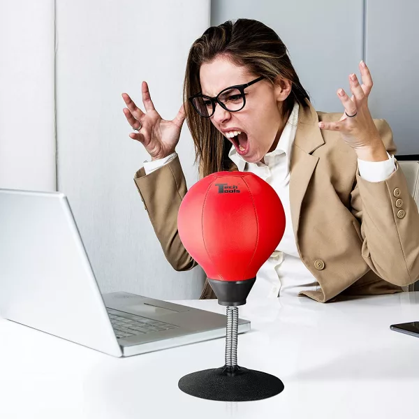 Woman Screaming At Laptop With Desktop Punching Bag next to her