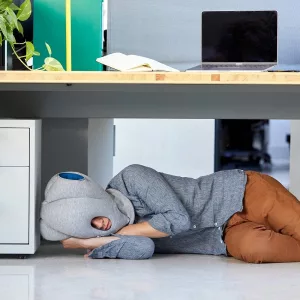 Woman Sleeping Under Desk In Ostrich Portable Nap Pillow