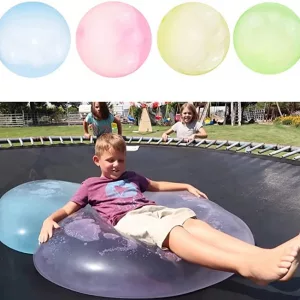 Young Boy Laying On Giant Inflatable Water Bubbles Ontop of Trampoline