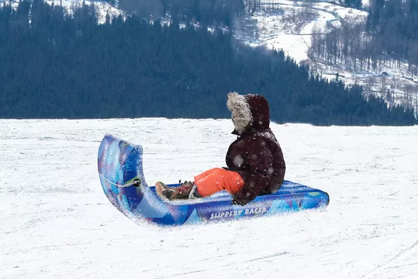 Young man riding on the Flexible Toboggan Sled